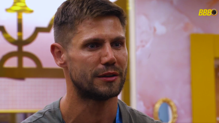 Registro da BBB 26 Jonas polêmica com o brother pensativo na área externa.